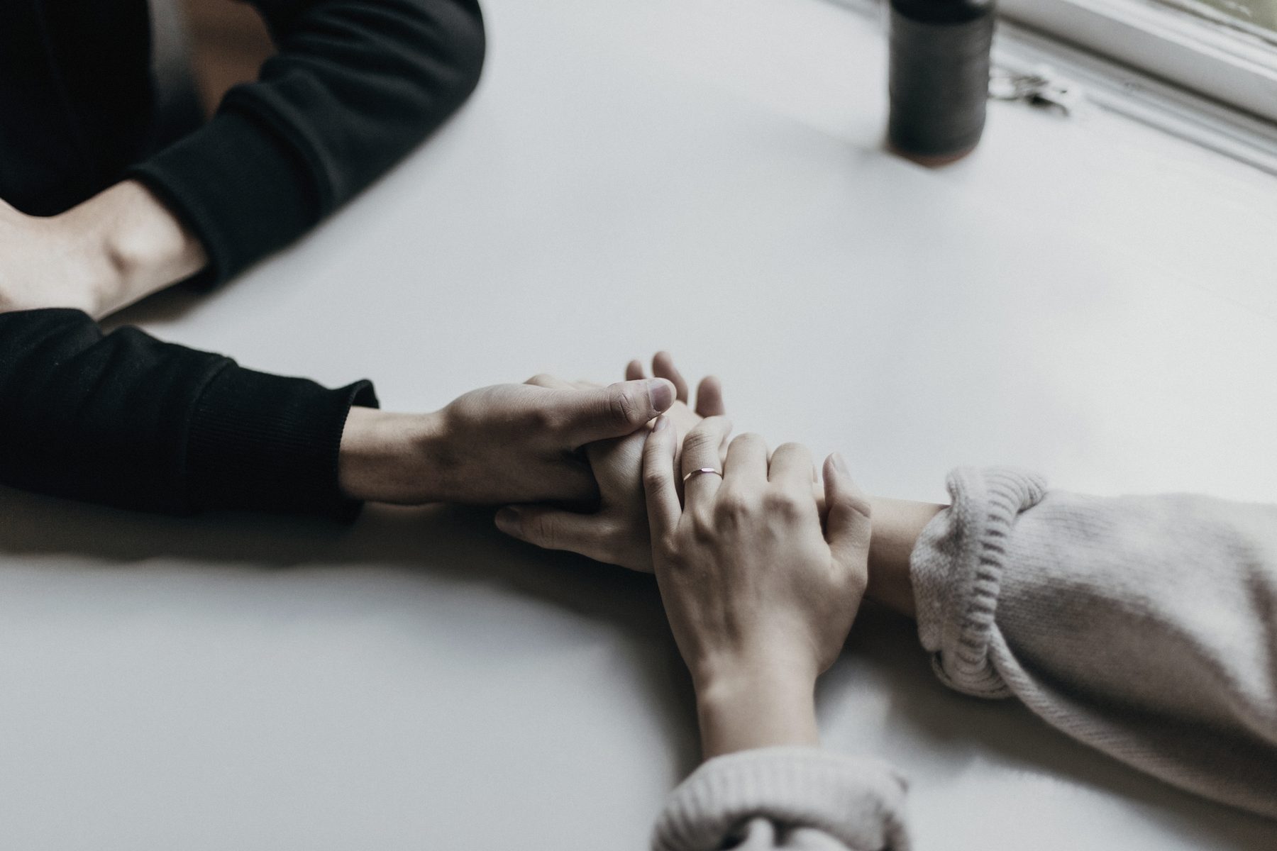 Two people holding hands across a white table
