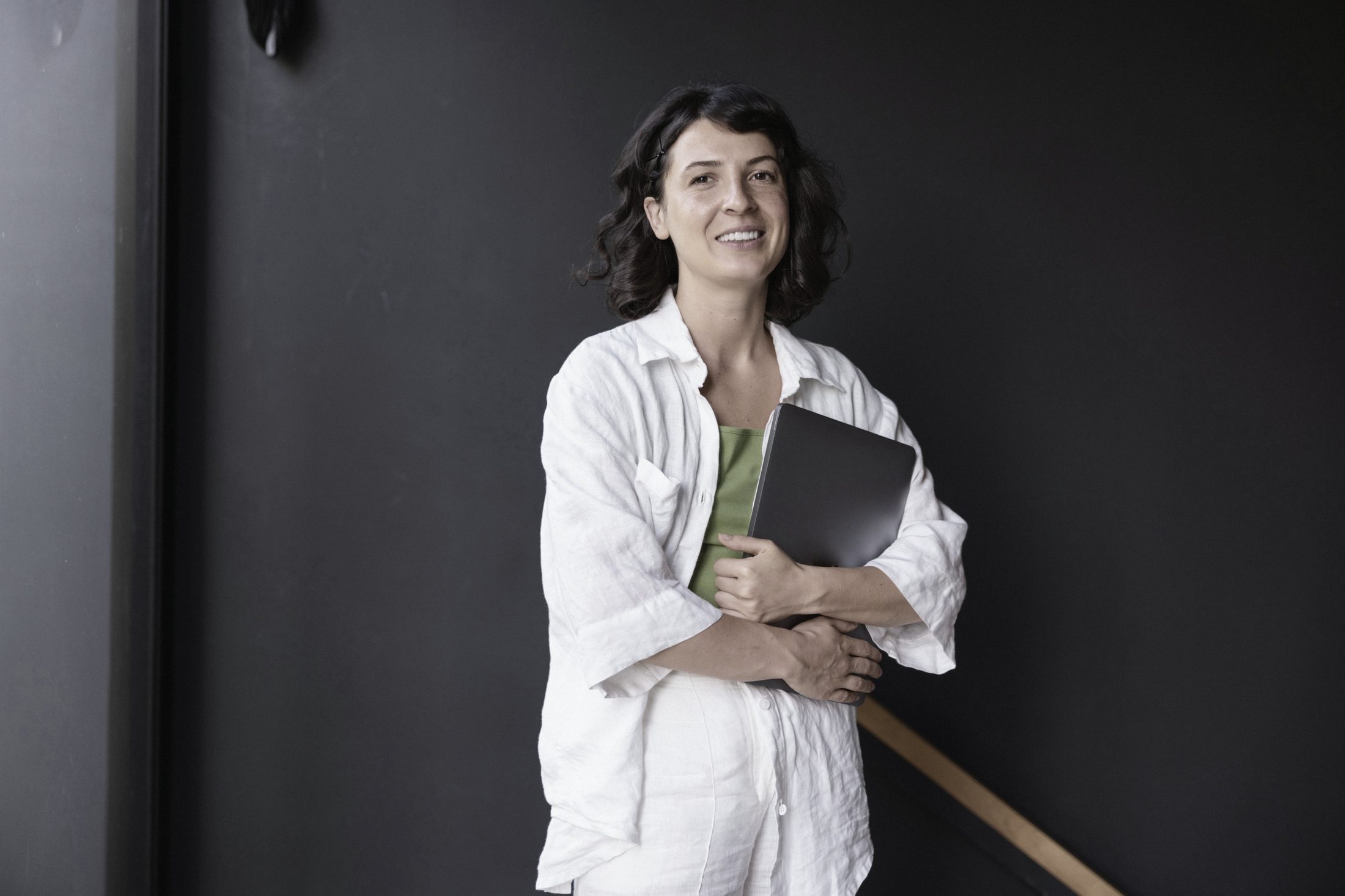 Dr. Lucía Serrano in a white coat, smiling, holding a folder against a dark wall