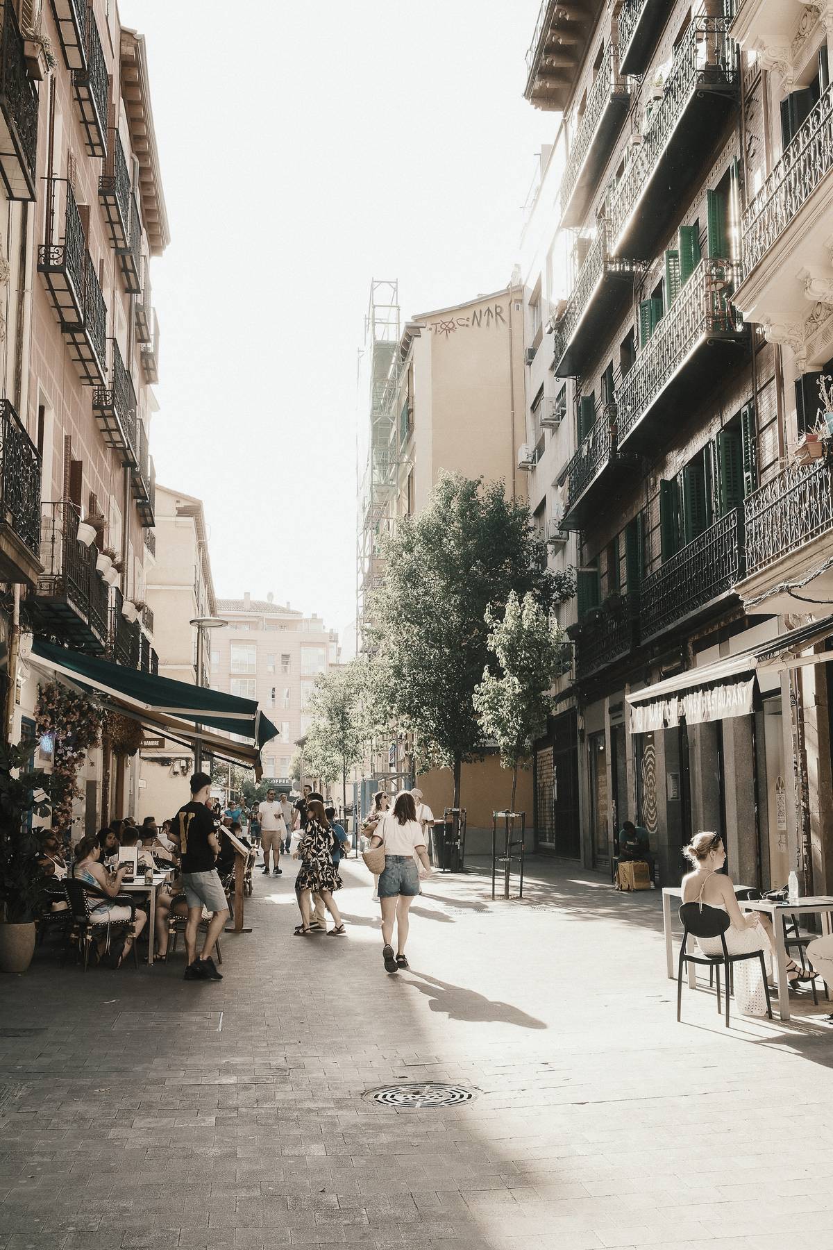 People walking down a sunny street of the Barrio de las Letras