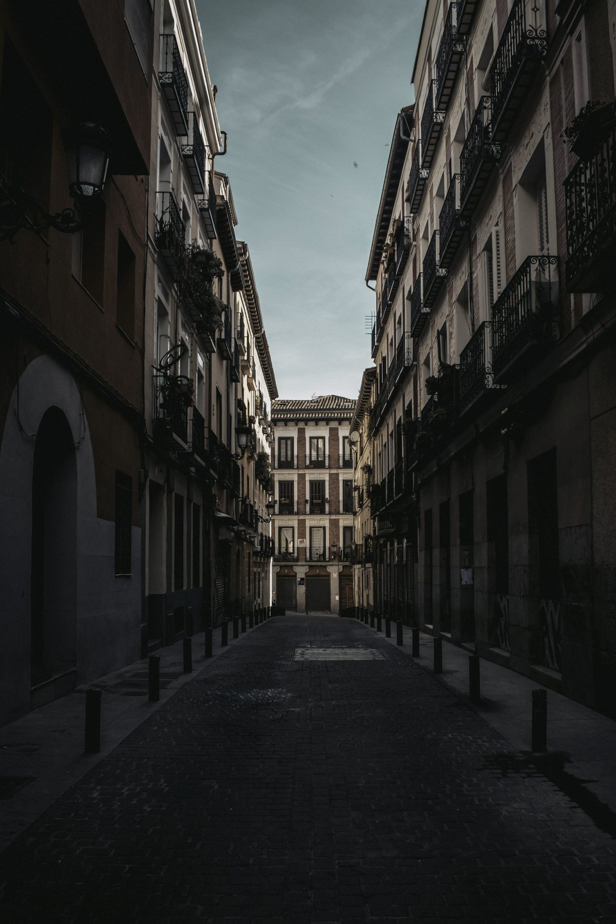 A narrow street at dusk with balconies on both sides