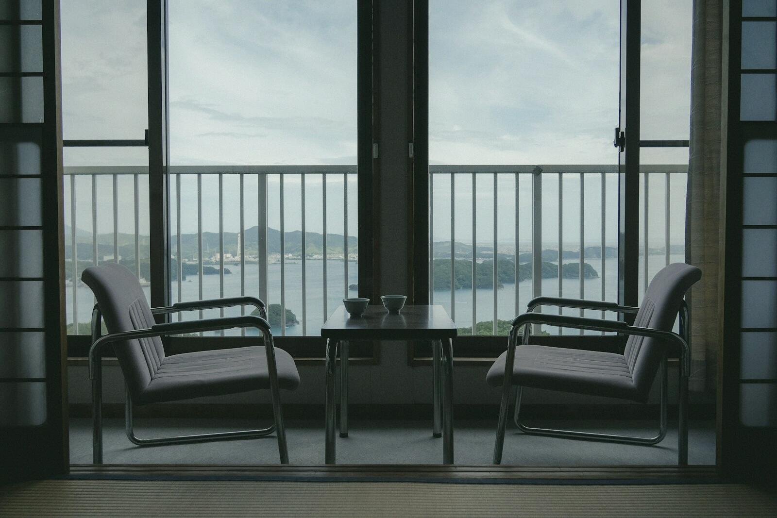 Two chairs facing each other by a large window over the sea