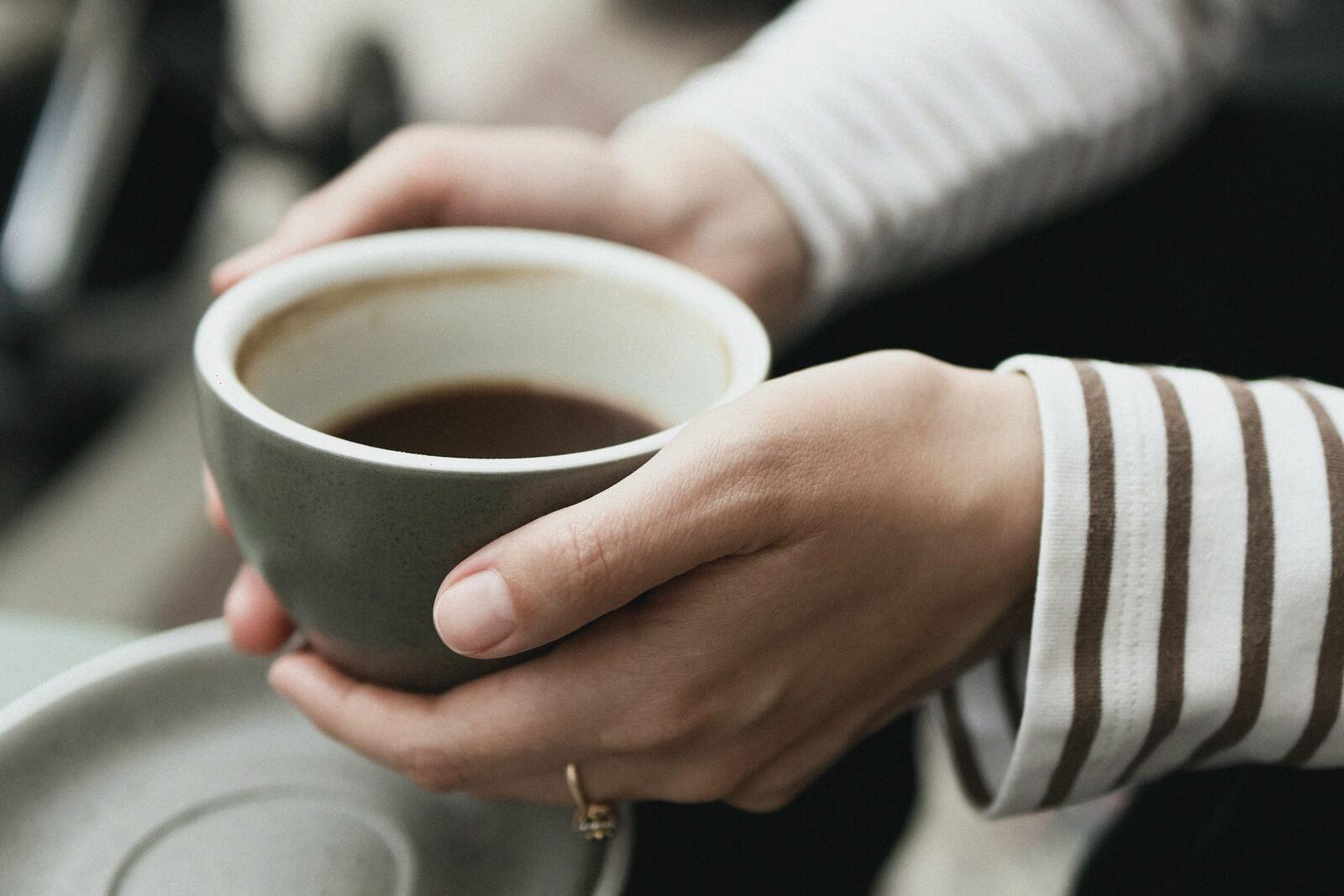 Two hands holding a warm cup of coffee