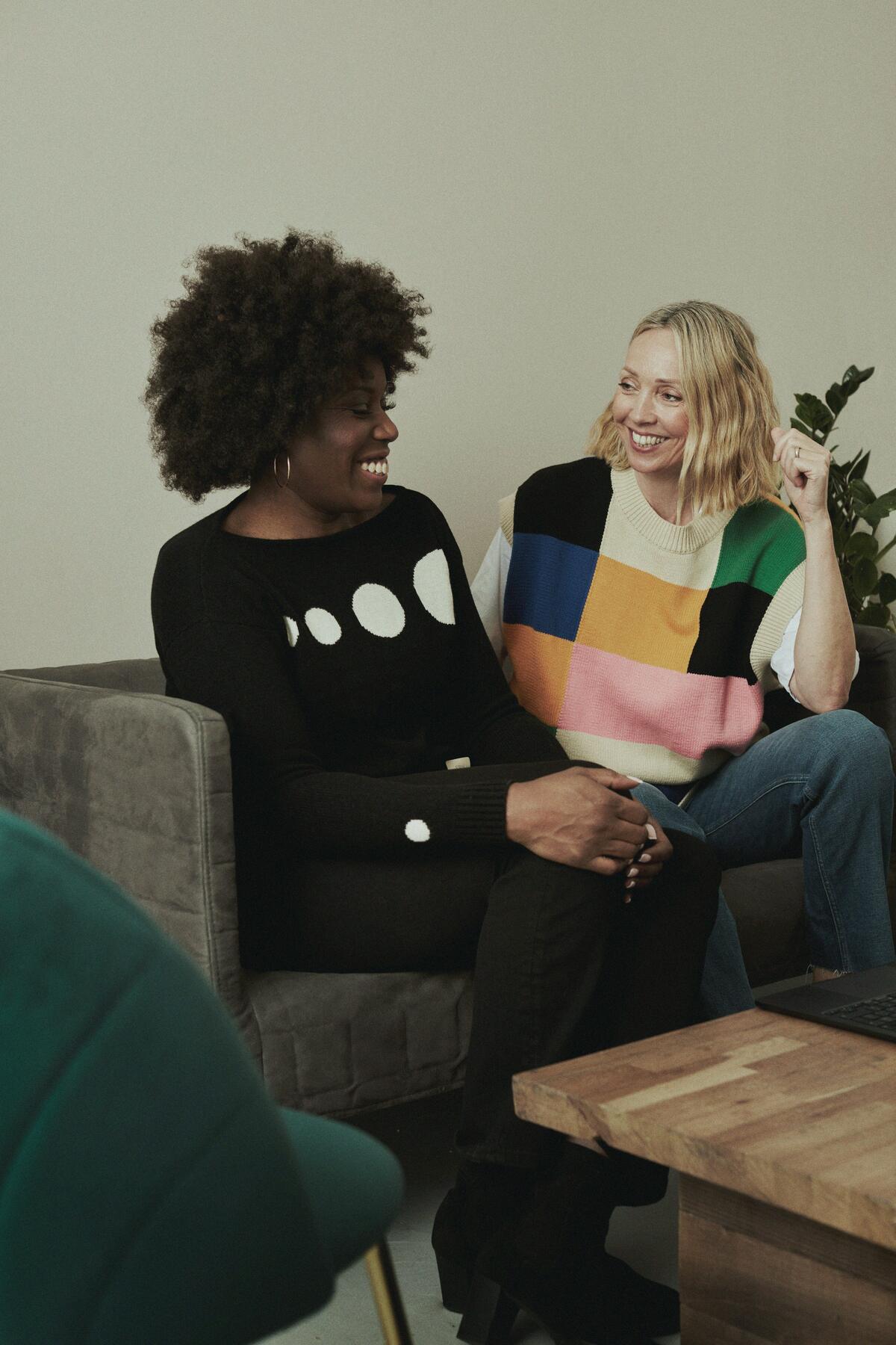 Two women talking and laughing on a sofa