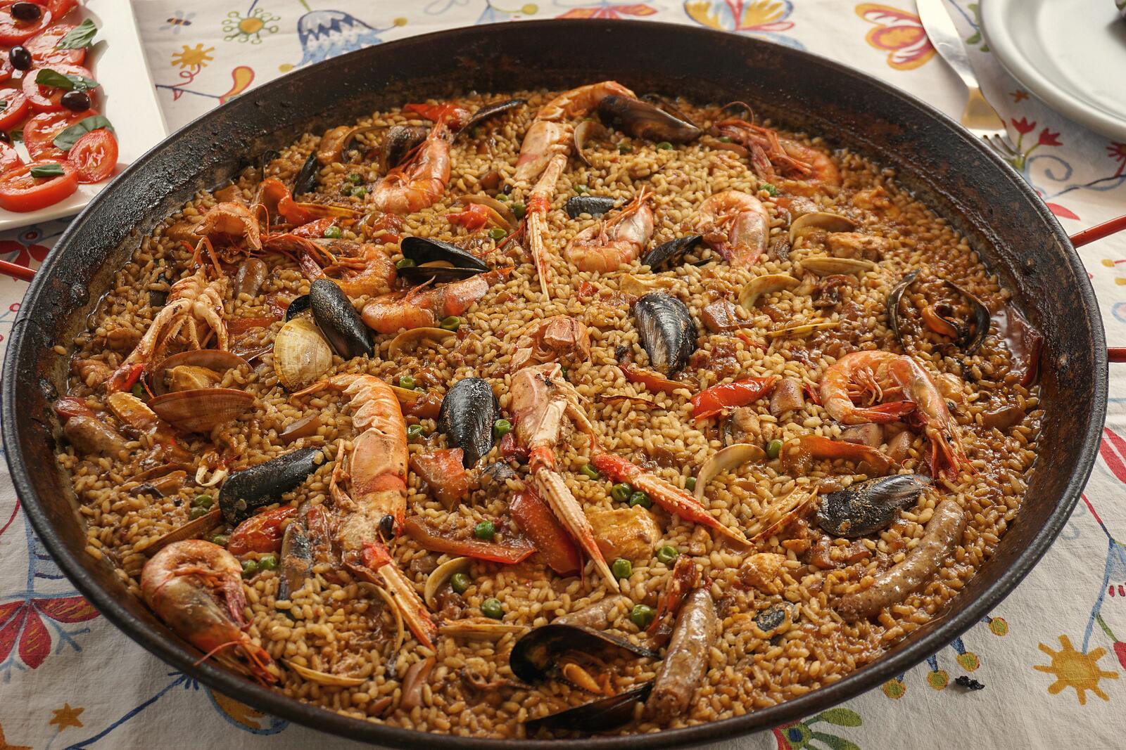 A seafood rice in its pan, seen from above, on a patterned tablecloth