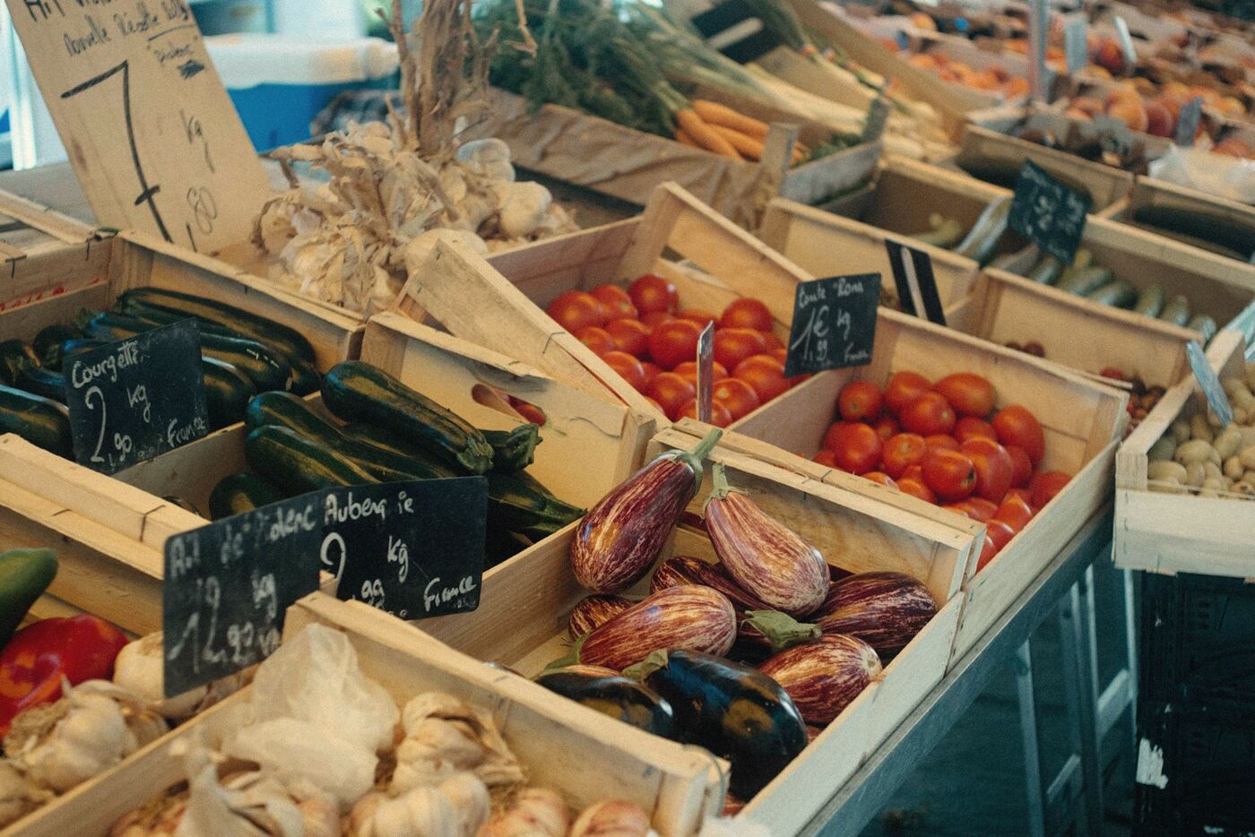 Crates of aubergines, tomatoes and garlic at a market stall