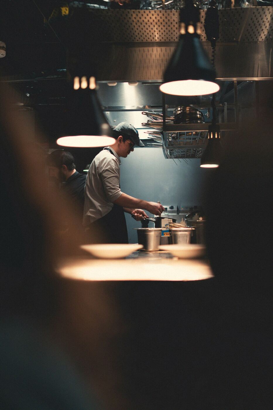 A cook under the heat lamps at the pass