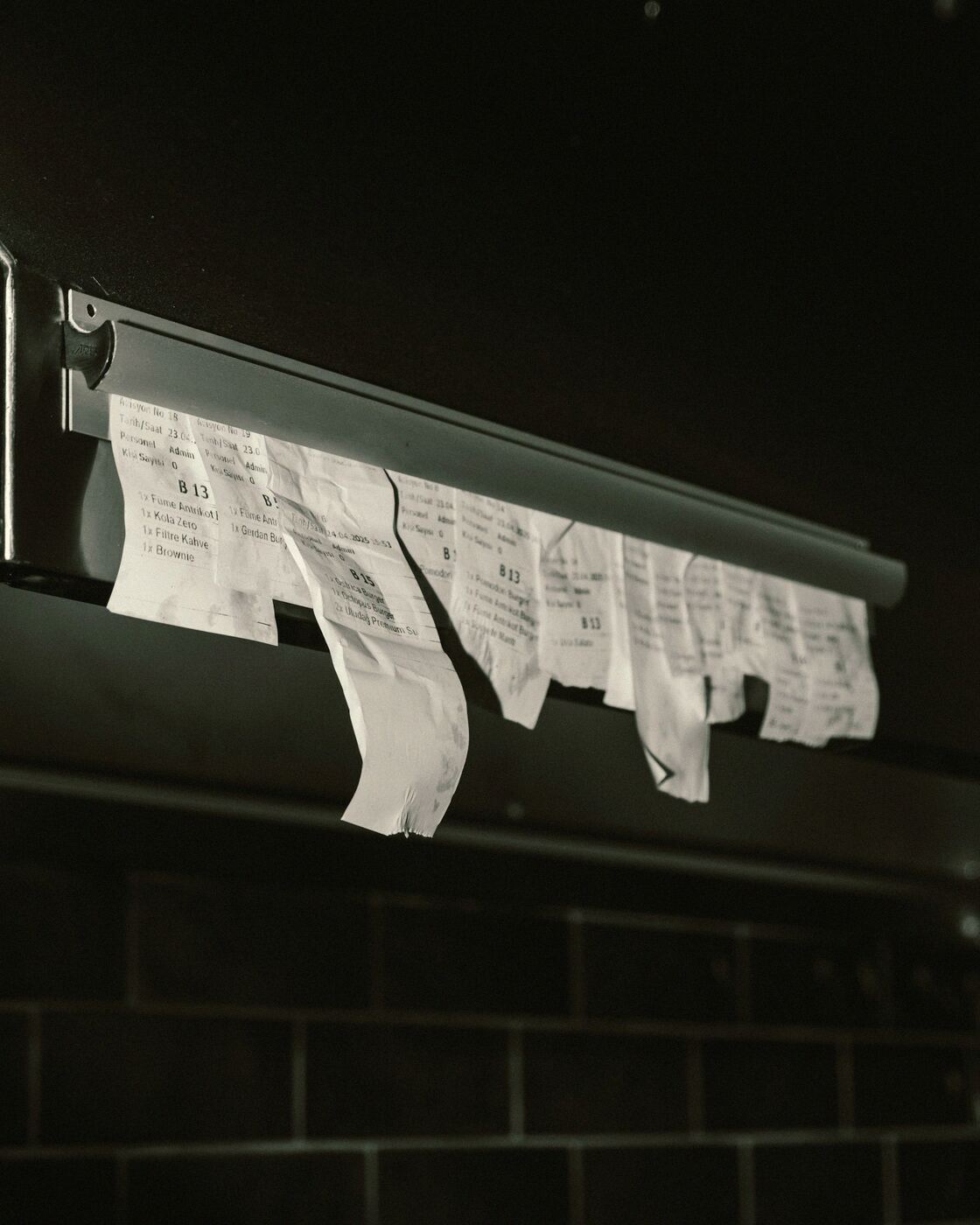 Kitchen tickets hanging from a metal rail