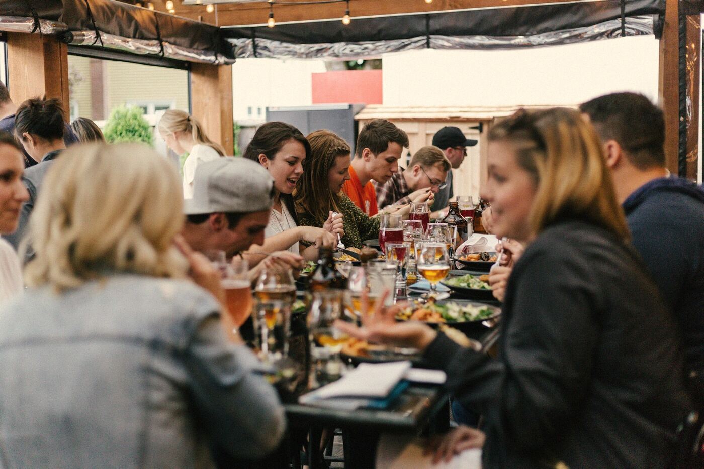 A group eating together at a long table on a covered terrace