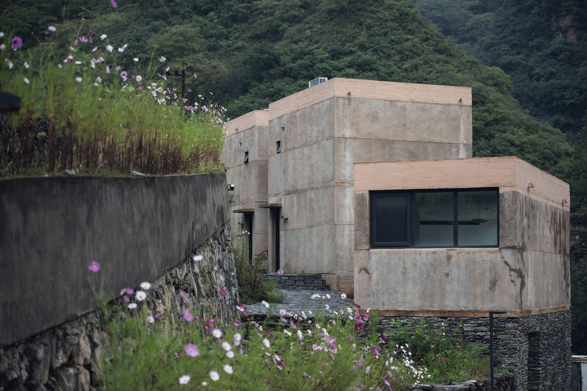 Earth-coloured concrete house stepping down a wooded slope