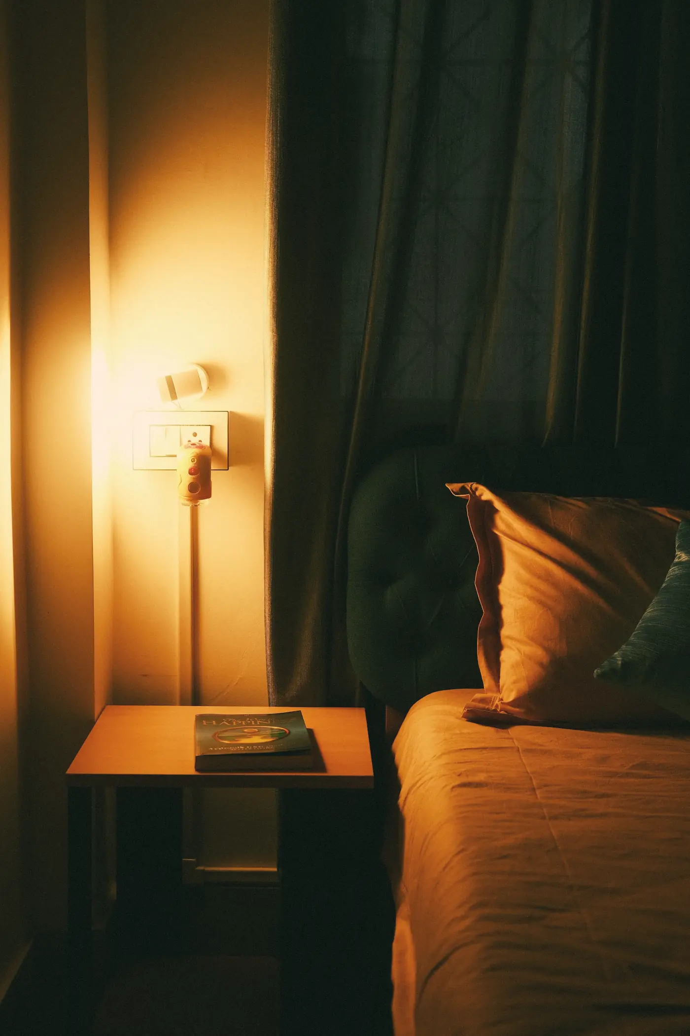 A bedside lamp glowing next to a made bed