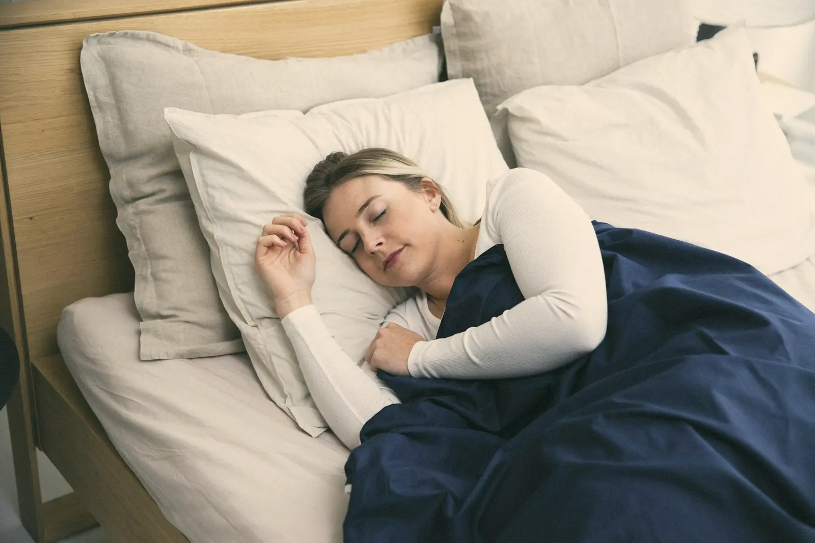 A woman asleep under a navy blanket