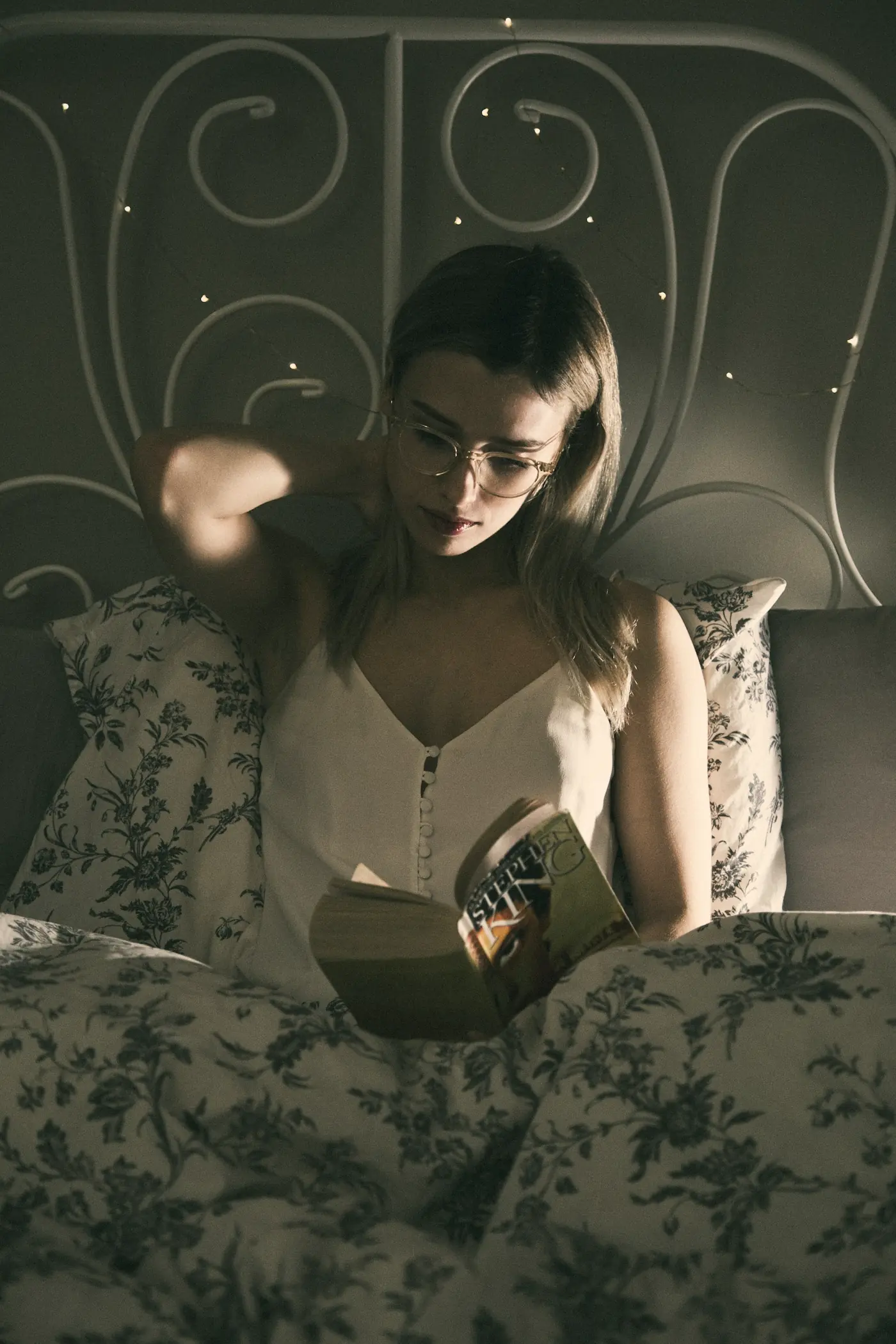 A woman reading in bed by lamplight