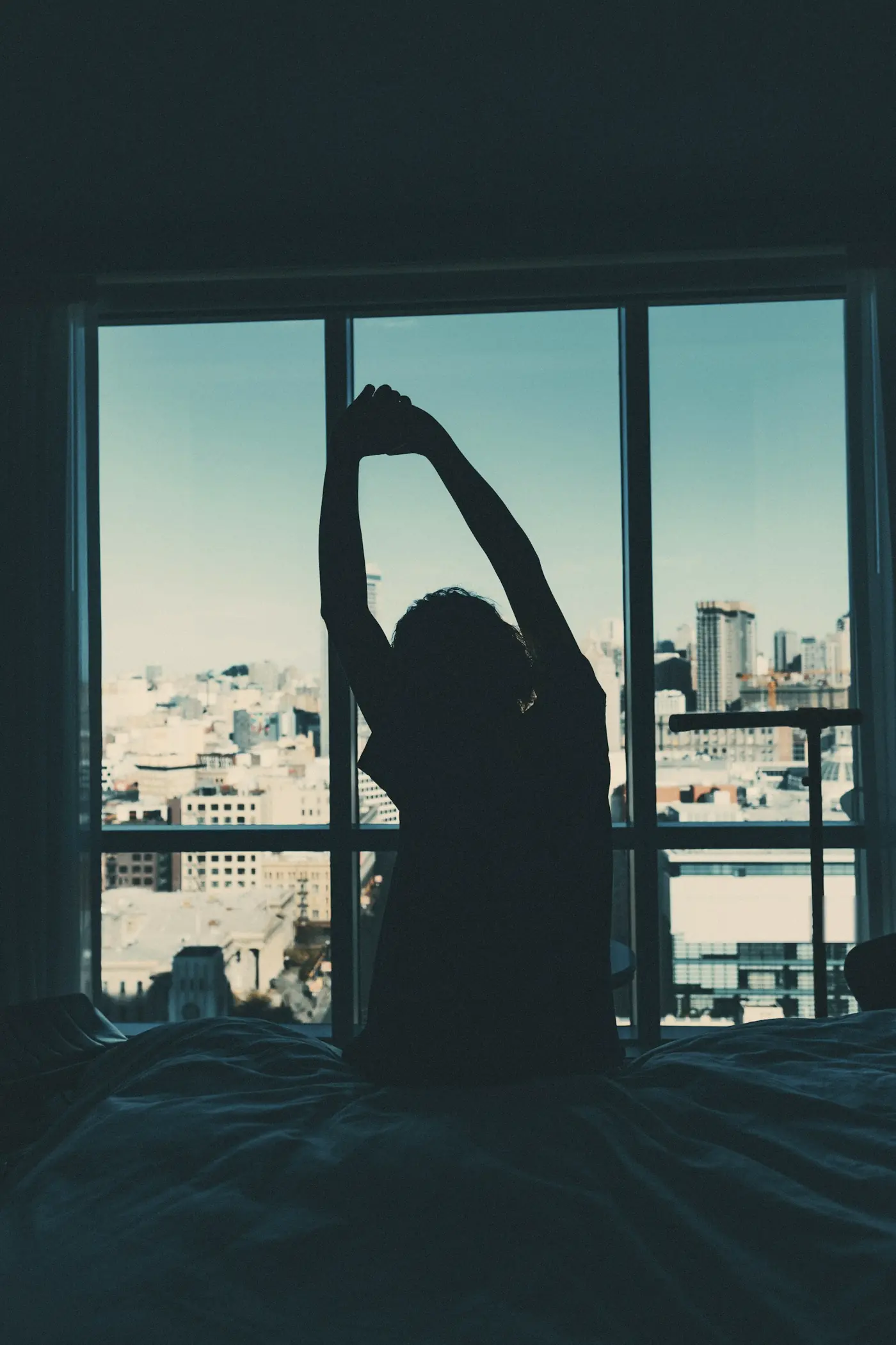 A person stretching in front of a city window at dawn