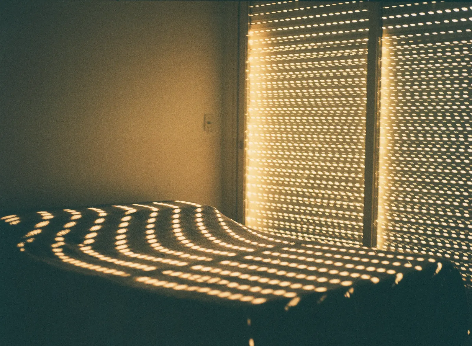Morning light through blinds striping a bed