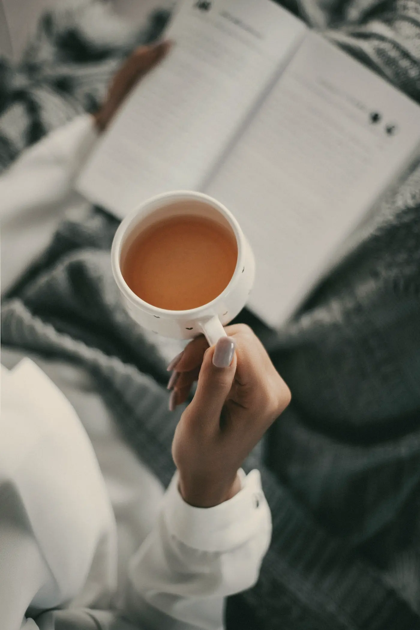 A cup of tea held over an open book