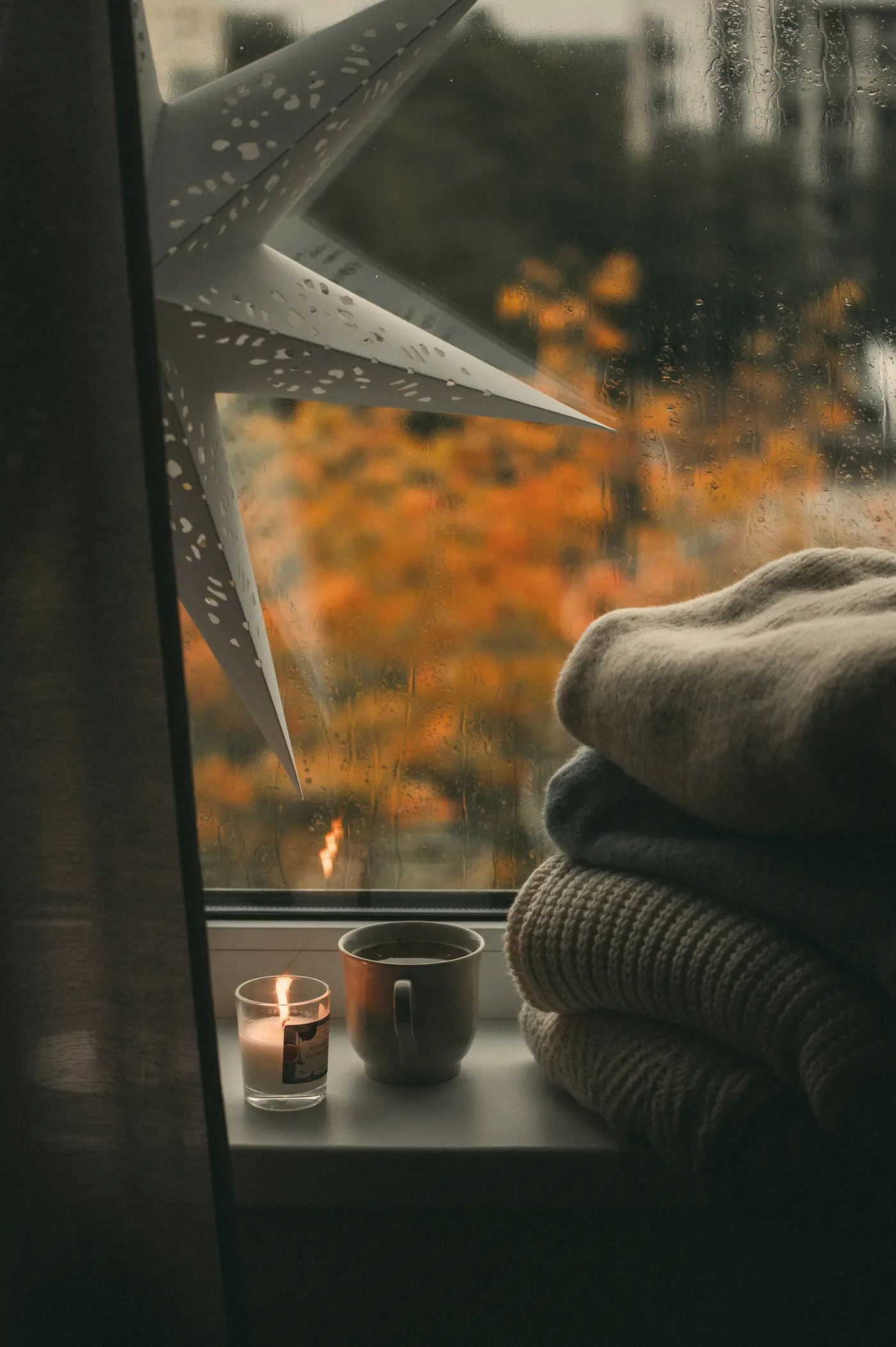 Candles and a folded blanket on an autumn window sill