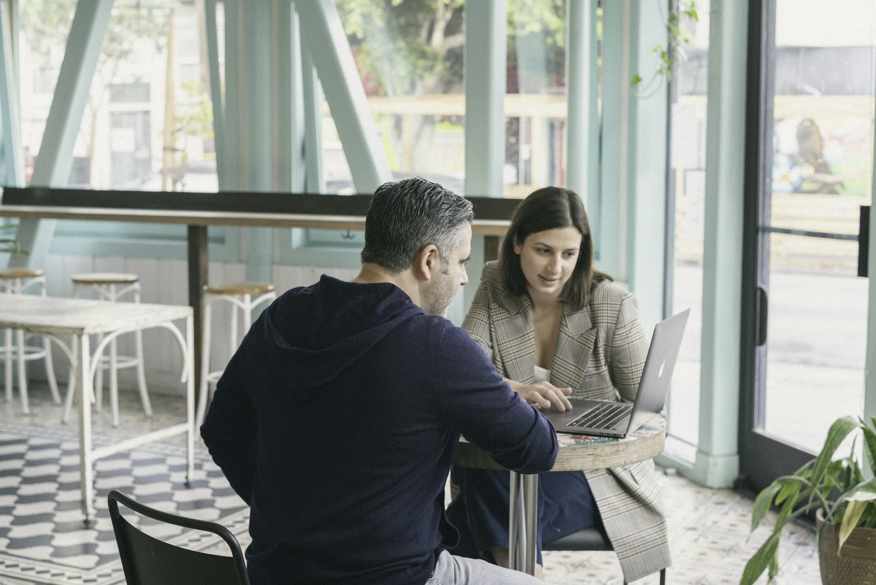 An adviser and a client working on a laptop at a café table